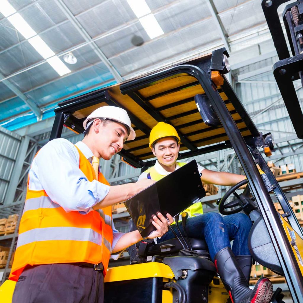 Asian forklift truck driver and foreman in storage